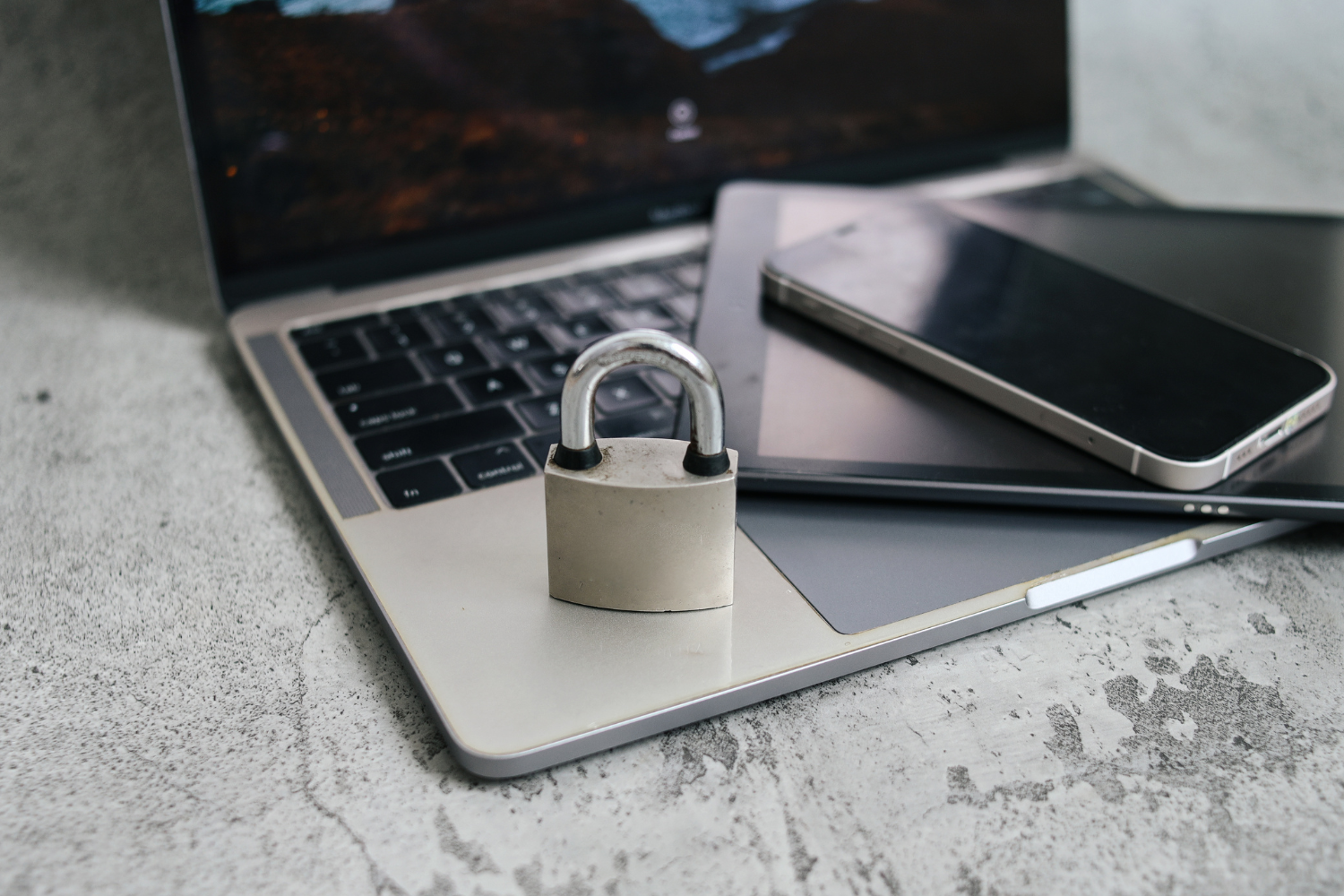 A lock sat on the corner of an open laptop with a phone